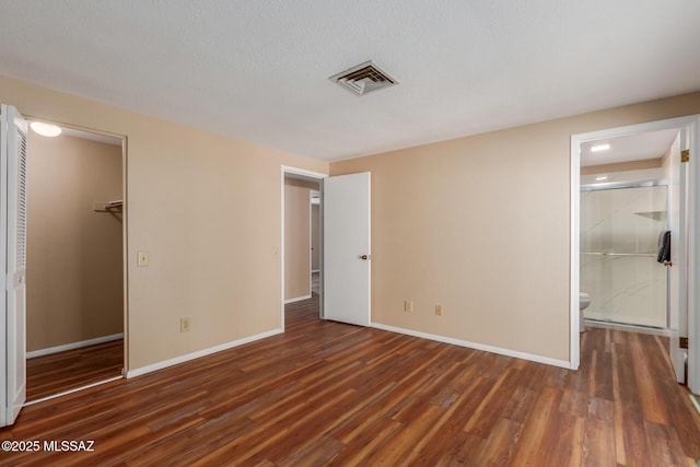 unfurnished bedroom with a closet, visible vents, baseboards, and wood finished floors