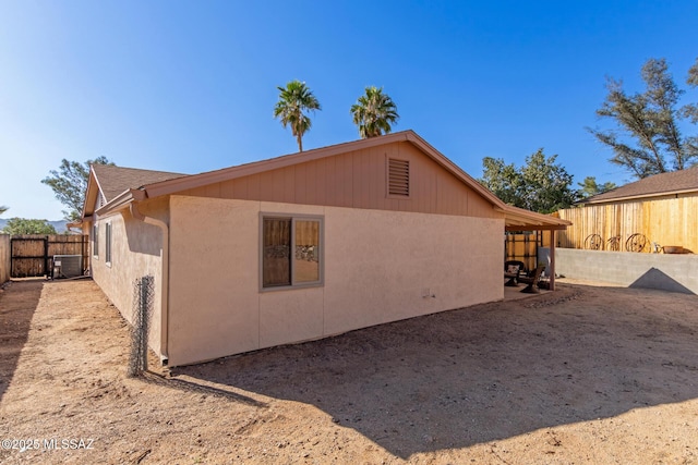 back of house with central AC unit, a fenced backyard, and stucco siding