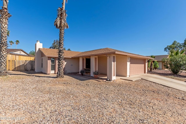 view of front of house featuring stucco siding, driveway, fence, an attached garage, and a chimney
