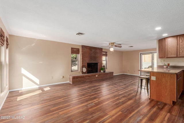 kitchen featuring visible vents, a breakfast bar, a ceiling fan, and dark wood-style flooring
