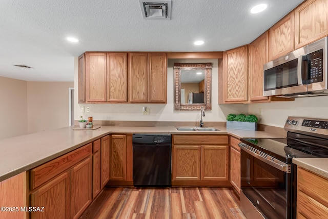 kitchen featuring visible vents, light wood-style flooring, a sink, a textured ceiling, and stainless steel appliances