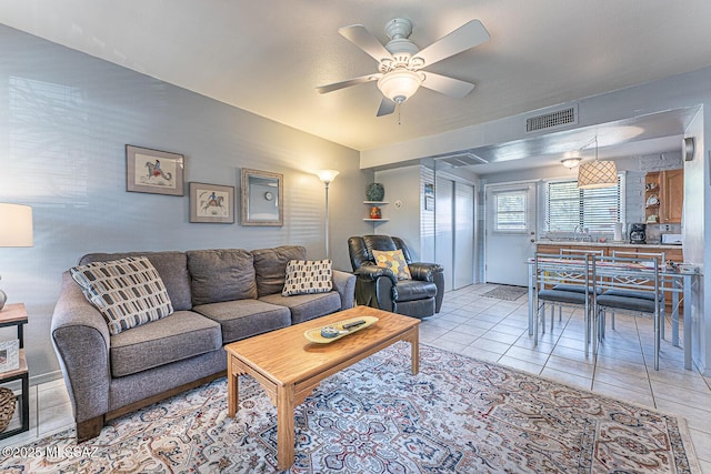 living area featuring light tile patterned floors, visible vents, and a ceiling fan