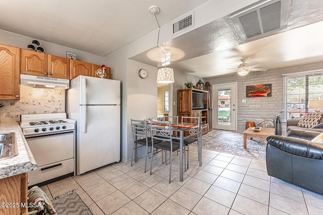 kitchen with white appliances, a wealth of natural light, visible vents, and under cabinet range hood