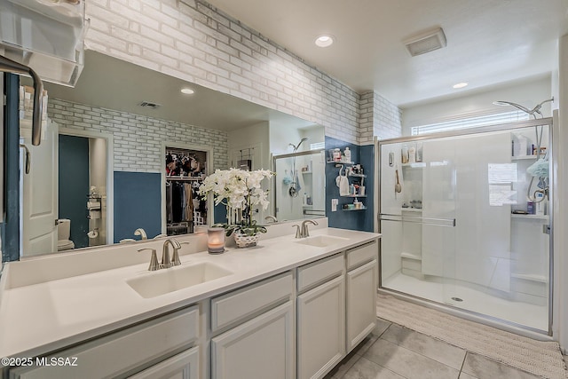 full bathroom featuring a shower stall, tile patterned floors, brick wall, and a sink