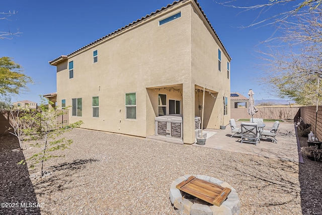 rear view of property with stucco siding, a fenced backyard, and a patio area