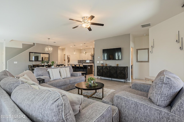 living room featuring recessed lighting, visible vents, light wood-style floors, and ceiling fan with notable chandelier