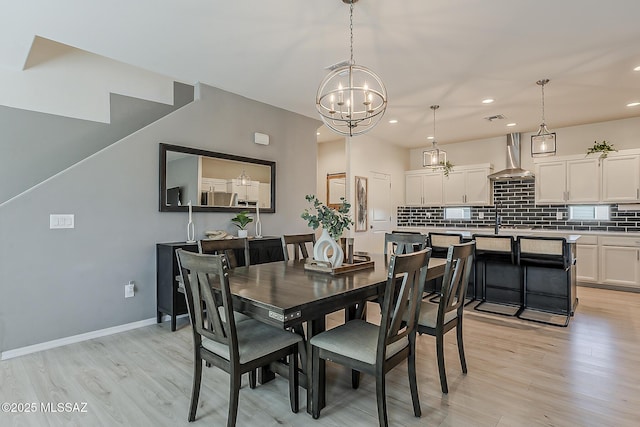 dining area featuring a chandelier, visible vents, light wood-type flooring, and baseboards