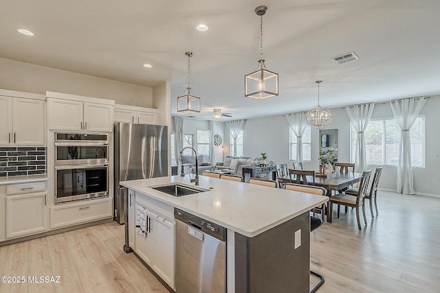 kitchen with visible vents, light countertops, decorative backsplash, stainless steel appliances, and a sink