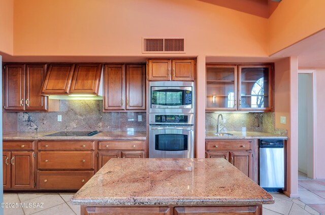 5460 N Paseo Pescado, Tucson, AZ 85718 - kitchen featuring appliances with stainless steel finishes, premium range hood, brown cabinets, a towering ceiling, and light tile patterned floors
