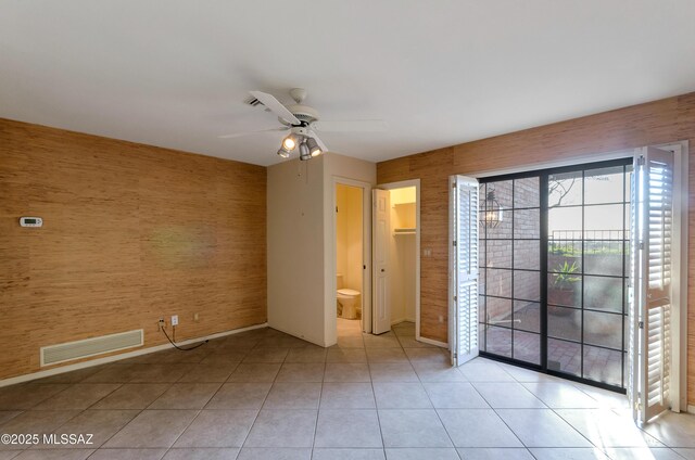 5460 N Paseo Pescado, Tucson, AZ 85718 - unfurnished bedroom featuring access to outside, light tile patterned floors, a ceiling fan, ensuite bathroom, and wood walls