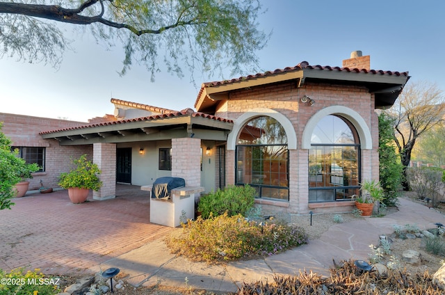 5460 N Paseo Pescado, Tucson, AZ 85718 - view of front of house with a tile roof, brick siding, and a patio area