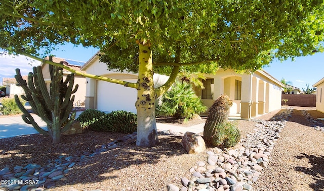 obstructed view of property featuring roof mounted solar panels, fence, and stucco siding