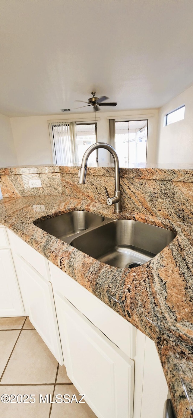kitchen featuring a sink, white cabinetry, light stone counters, and light tile patterned flooring