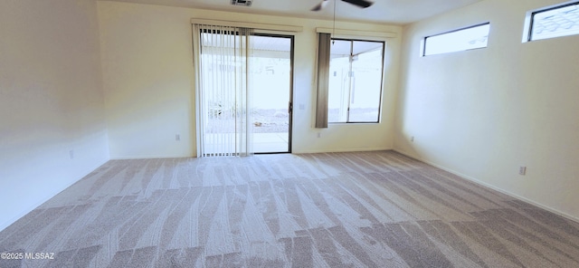 unfurnished room with carpet floors, a ceiling fan, visible vents, and plenty of natural light