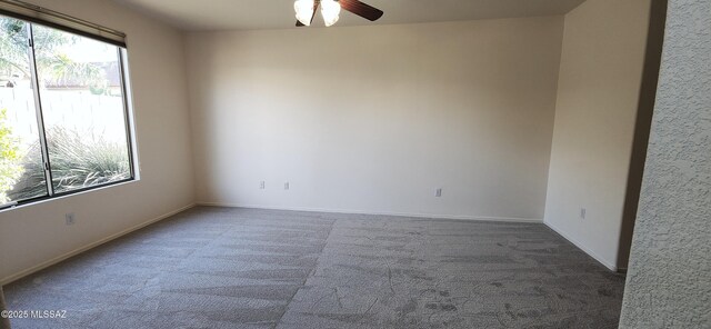 carpeted empty room featuring ceiling fan and baseboards