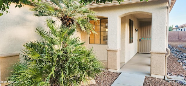 property entrance featuring stucco siding and fence