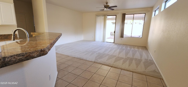interior space featuring a ceiling fan, light colored carpet, and light tile patterned floors