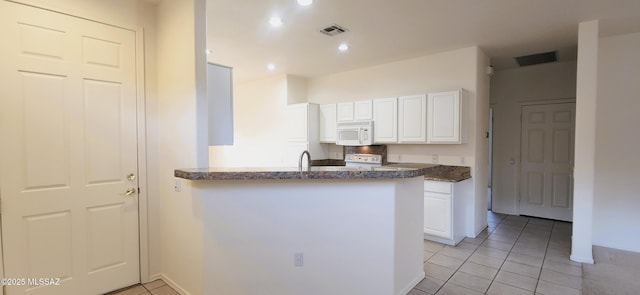 kitchen with white cabinets, light tile patterned flooring, visible vents, and white microwave