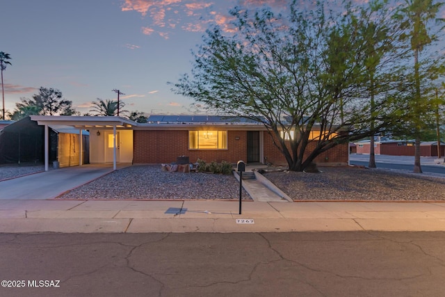 7267 E Eastview Dr, Tucson, AZ 85710 - view of front facade with roof mounted solar panels, brick siding, driveway, and a carport