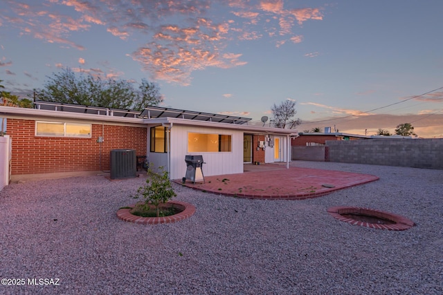 7267 E Eastview Dr, Tucson, AZ 85710 - back of house at dusk featuring a patio, central AC, a fenced backyard, and brick siding