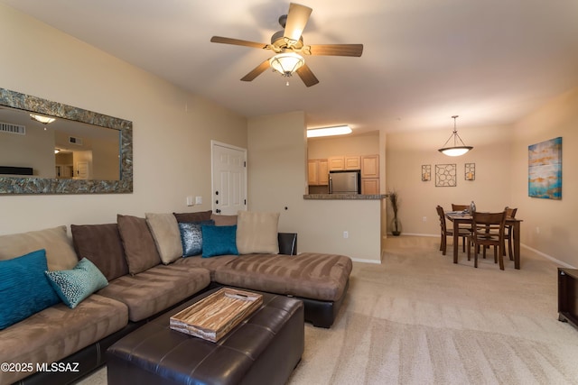 living room featuring light carpet, visible vents, baseboards, and a ceiling fan