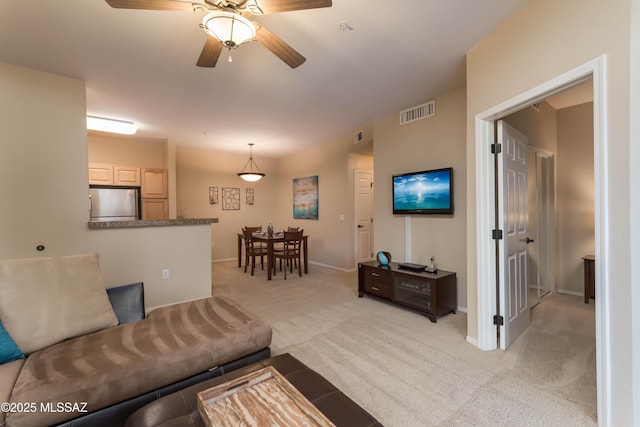 living room featuring baseboards, a ceiling fan, visible vents, and light carpet