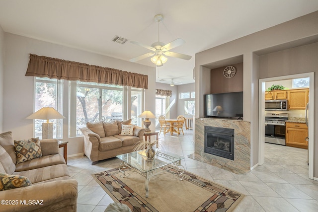1117 E Regent Dr, Oro Valley, AZ 85755 - living room with visible vents, baseboards, ceiling fan, a tile fireplace, and light tile patterned flooring