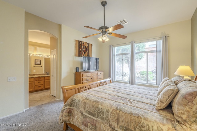1117 E Regent Dr, Oro Valley, AZ 85755 - bedroom featuring visible vents, a ceiling fan, ensuite bath, arched walkways, and light colored carpet