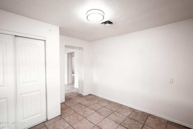 unfurnished bedroom with light tile patterned floors, visible vents, baseboards, and a closet
