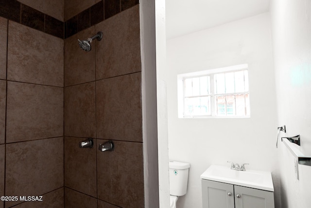full bathroom with vanity, toilet, and a tile shower