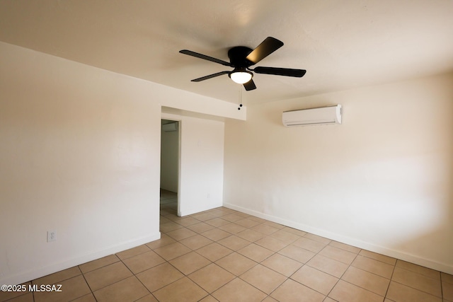 empty room featuring a wall unit AC, light tile patterned floors, a ceiling fan, and baseboards