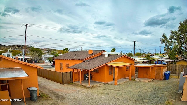 back of house with a patio, a shingled roof, driveway, and fence