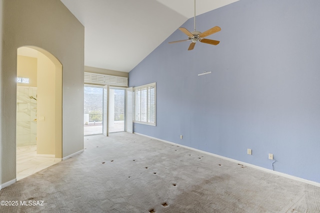 carpeted spare room featuring baseboards, arched walkways, ceiling fan, and high vaulted ceiling