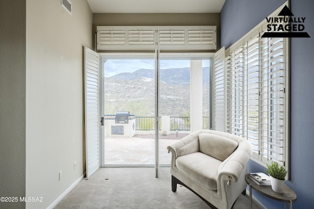 living area with a mountain view, a wealth of natural light, carpet flooring, and visible vents