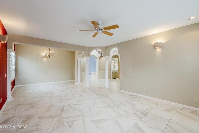 spare room with baseboards, arched walkways, ceiling fan with notable chandelier, and decorative columns
