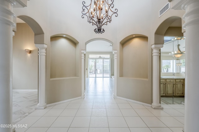 hallway featuring a towering ceiling, baseboards, visible vents, and a wealth of natural light
