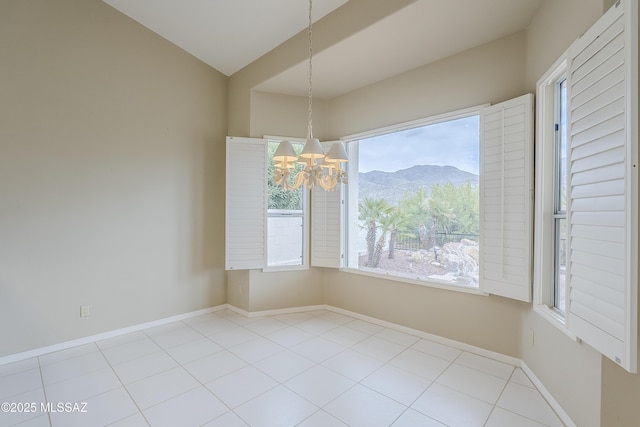 unfurnished dining area featuring baseboards, a notable chandelier, tile patterned flooring, and a mountain view