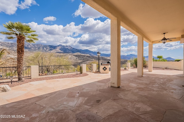view of patio featuring a mountain view, fence, and a ceiling fan