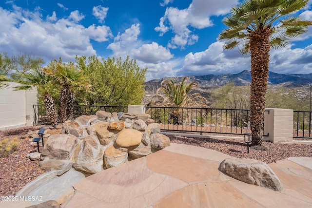 view of patio / terrace featuring fence and a mountain view