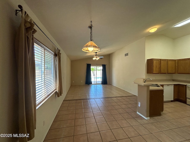kitchen featuring vaulted ceiling, light tile patterned floors, light countertops, visible vents, and white dishwasher