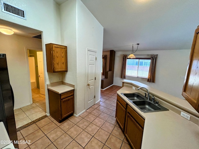 kitchen with a sink, visible vents, light tile patterned floors, and black refrigerator
