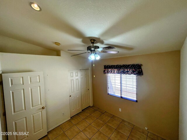 unfurnished bedroom featuring a closet, ceiling fan, tile patterned flooring, and a textured ceiling
