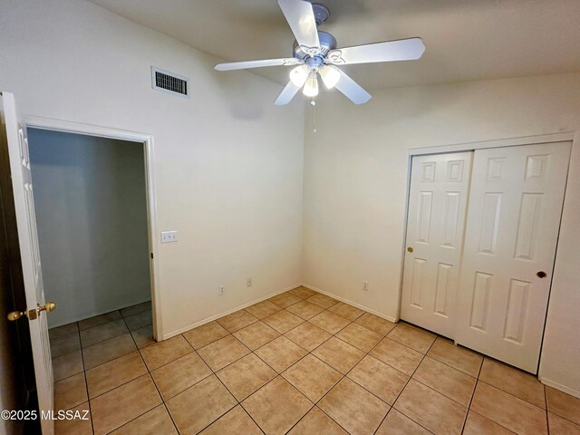 unfurnished bedroom featuring a closet, light tile patterned floors, ceiling fan, and visible vents