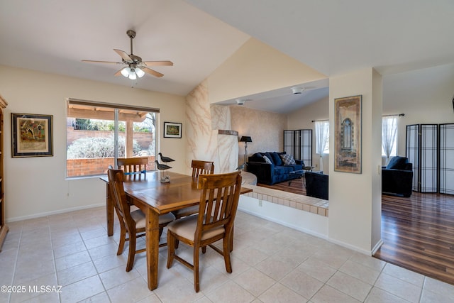 dining area featuring light tile patterned floors, baseboards, ceiling fan, and vaulted ceiling