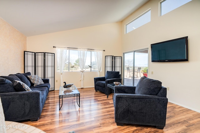 living room with high vaulted ceiling, baseboards, and wood finished floors