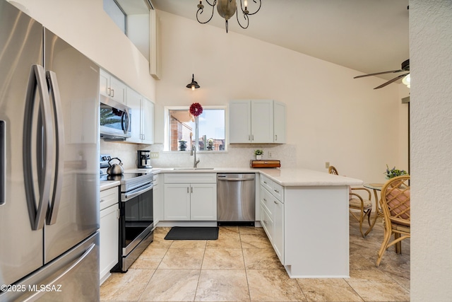 kitchen featuring a sink, backsplash, appliances with stainless steel finishes, a peninsula, and light countertops