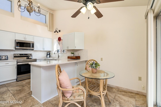 kitchen with tasteful backsplash, light countertops, appliances with stainless steel finishes, a peninsula, and a towering ceiling