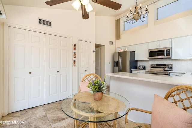 dining space with ceiling fan with notable chandelier, visible vents, and high vaulted ceiling