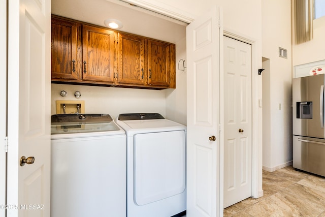 clothes washing area with washer and clothes dryer, visible vents, and cabinet space