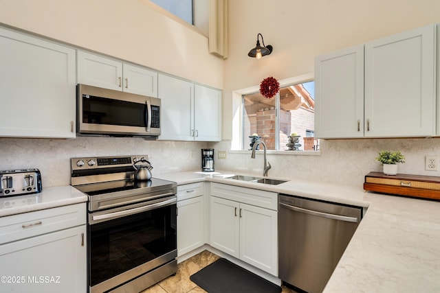kitchen with a sink, tasteful backsplash, white cabinetry, appliances with stainless steel finishes, and light countertops